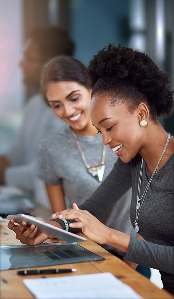 Two women smiling and looking at an tablet