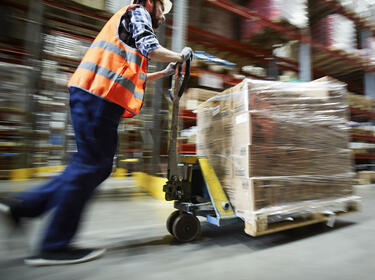 Warehouse worker using a pallet jack to move inventory